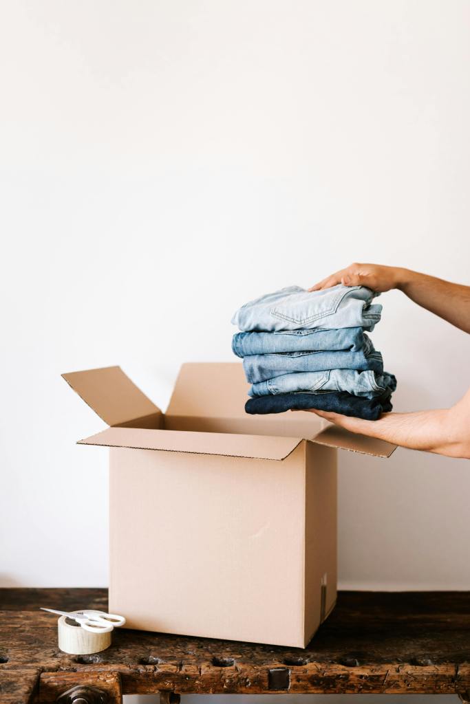 Stock image of someone folding clothes to put in a box.